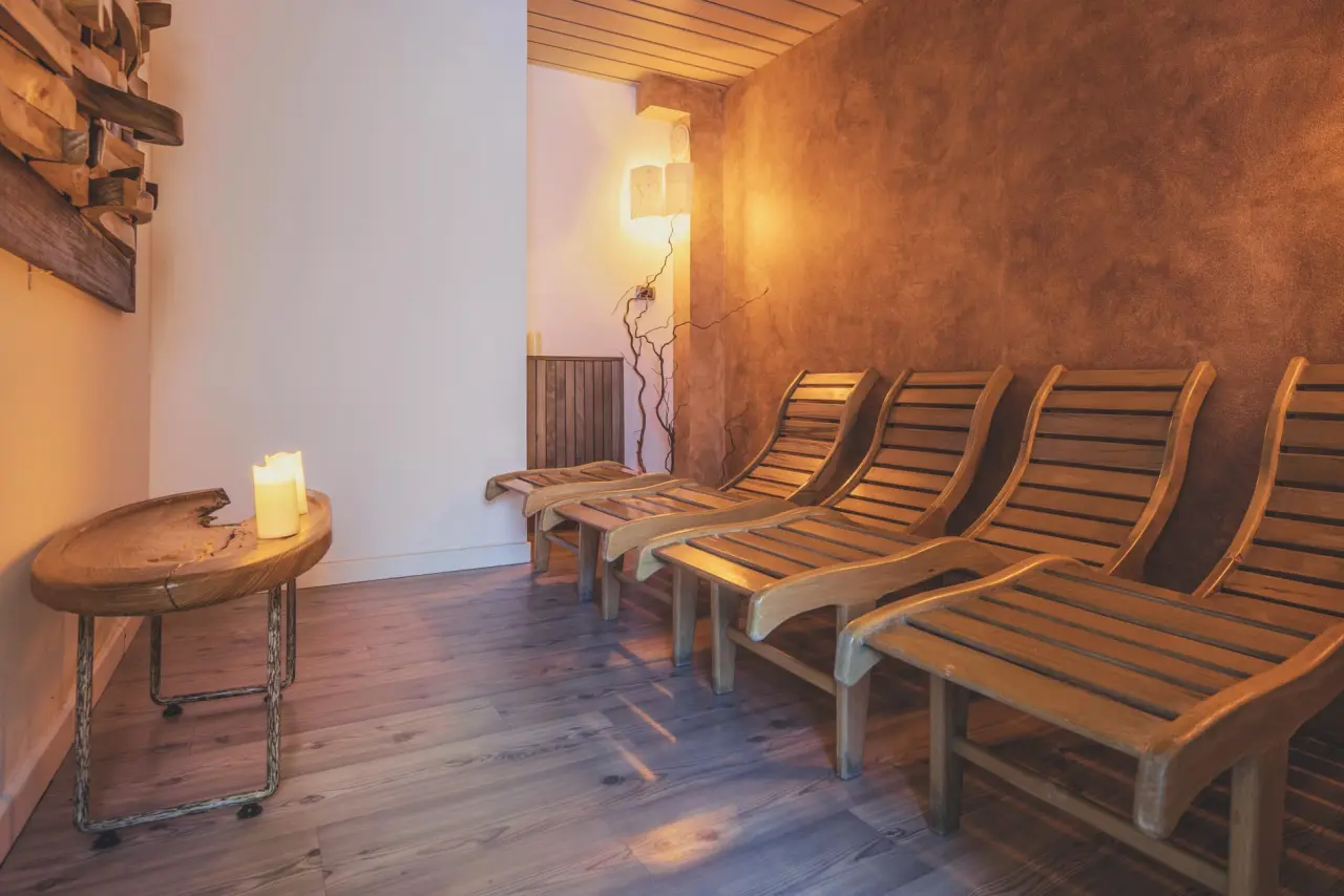 THE SUN Hotel Resort Clubresidence in Canazei – Gemütlicher Ruheraum mit Holzliegen und Kerzenlicht | Wellnesshotel Dolomiten