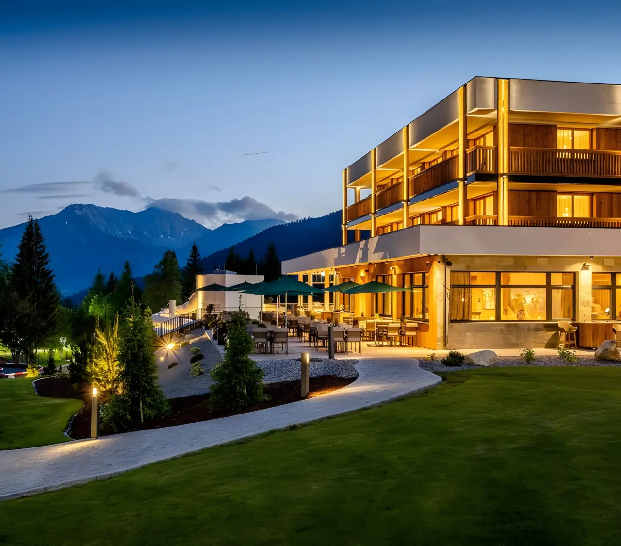 Zugspitz Resort in Ehrwald – Beleuchtete Hotelaußenansicht bei Dämmerung mit Bergpanorama | Wellnesshotel Tirol