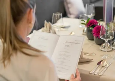 Hotel Exquisit in Oberstdorf – Gast studiert die Speisekarte im eleganten Hotelrestaurant | Wellnesshotel Allgäu