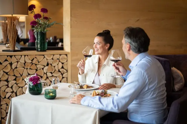 Hotel Exquisit in Oberstdorf – Paar genießt ein Abendessen mit Wein im stilvollen Hotelrestaurant | Wellnesshotel Allgäu