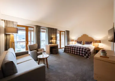 Hotel Exquisit in Oberstdorf – Geräumiges Hotelzimmer mit gemütlichem Sofa, Bett und Balkonzugang | Wellnesshotel Allgäu