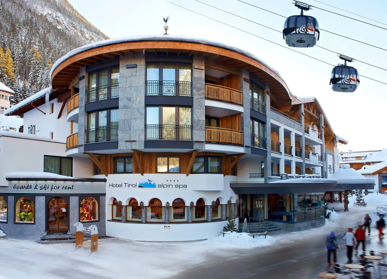 Hotel Tirol Alpin SPA in Ischgl – Hotelfassade im Winter mit Skigondeln und Alpin Spa Schriftzug | Wellnesshotel Tirol