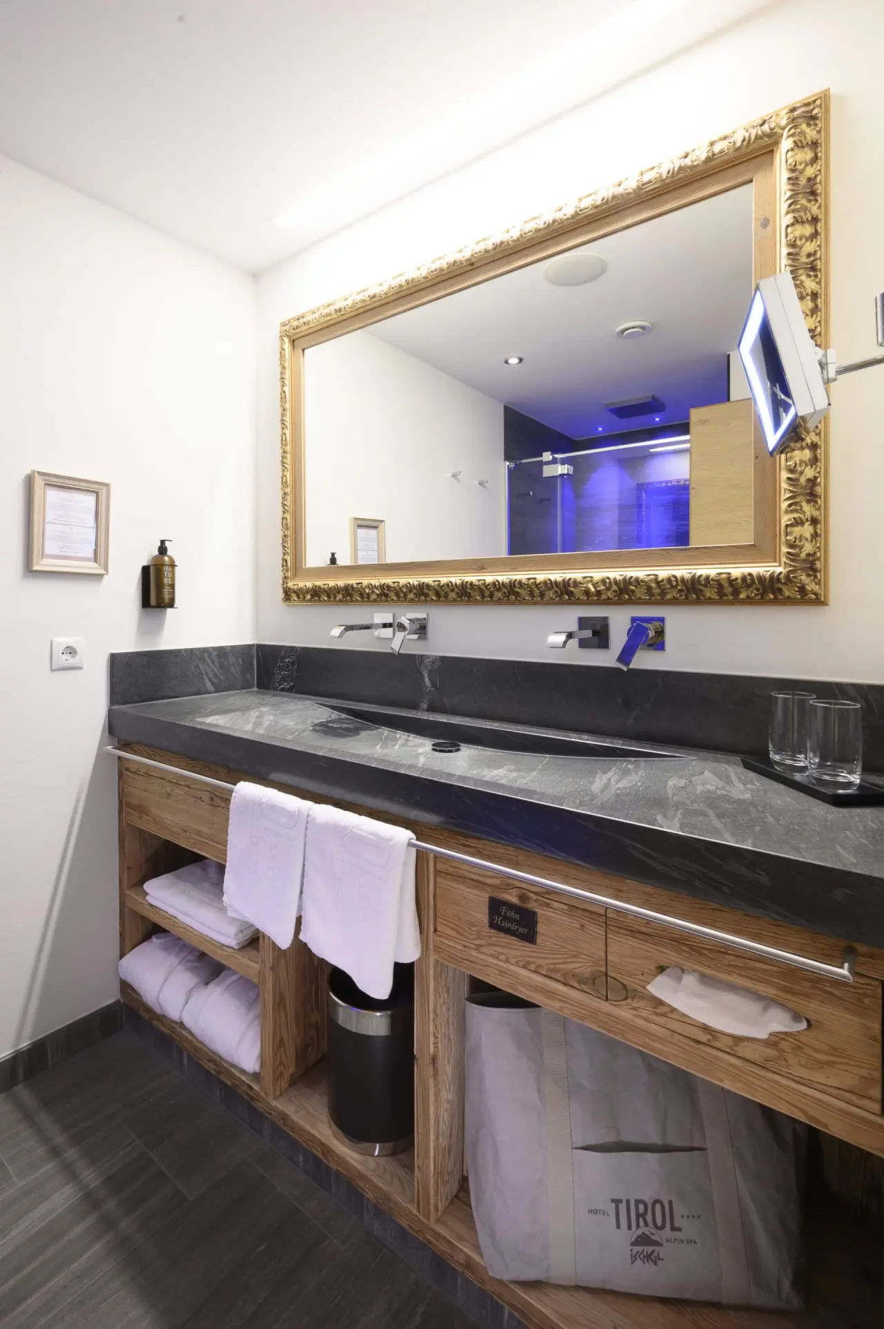 Hotel Tirol Alpin SPA in Ischgl – Elegantes Badezimmer mit großem Spiegel und blauer Lichtakzenten | Wellnesshotel Tirol