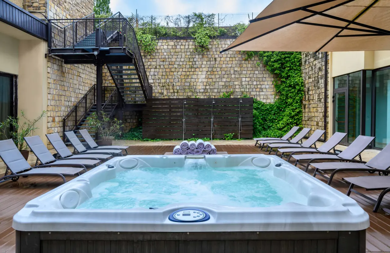 Hotel Leonardo in Lazise – Außen-Whirlpool mit Sonnenliegen und Steinmauer | Wellnesshotel Gardasee