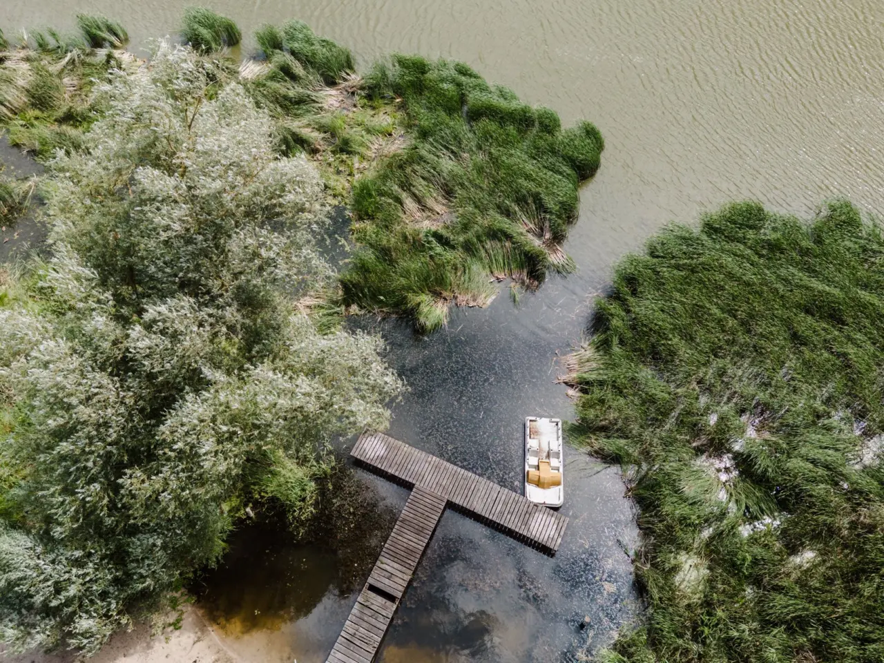 THE RESET HOTEL in Groß Plasten – Luftaufnahme eines Stegs mit Boot am Seeufer | Wellnesshotel Mecklenburg