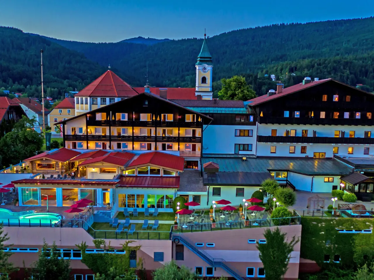 Wellnesshotel Hofbräuhaus in Bodenmais – Hotelanlage bei Dämmerung mit Poolbereich | Wellnesshotel Bayerischer Wald