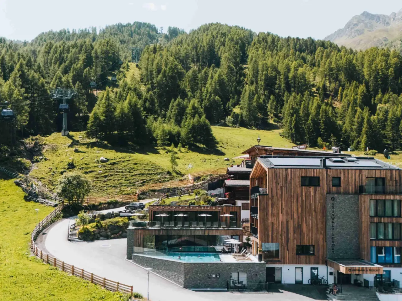 Aparthotel Grünwald Resort Sölden in Sölden – Hotelanlage im Sommer mit Außenpool und Bergen | Wellnesshotel Tirol