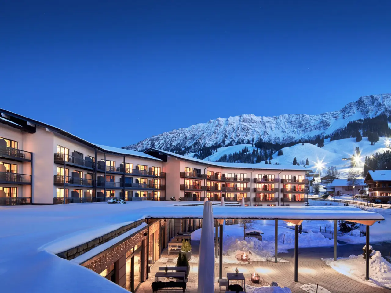 Panoramahotel Oberjoch in Bad Hindelang – Hotel-Außenansicht im Winter mit beleuchteten Balkonen | Wellnesshotel Allgäu