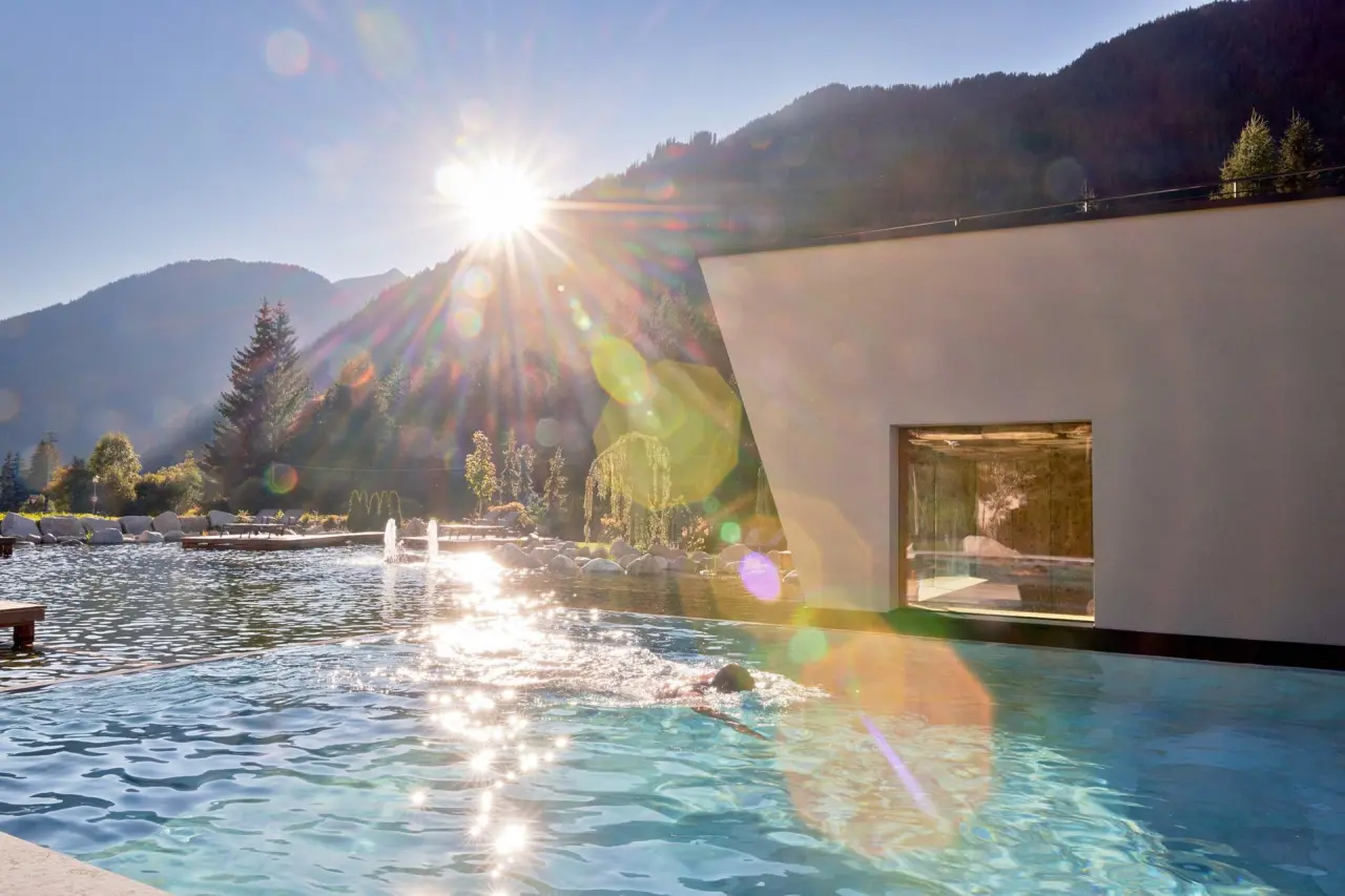 Fontis Luxury Spa Lodge in St. Martin in Gsies – Außenpool mit Schwimmer und Bergpanorama bei Sonnenschein | Wellnesshotel Südtirol