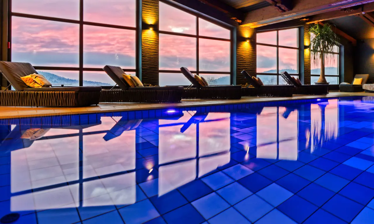 natura Hotel Bodenmais in Bodenmais – Hallenbad mit Liegen und Abendrot am Fenster | Wellnesshotel Bayerischer Wald