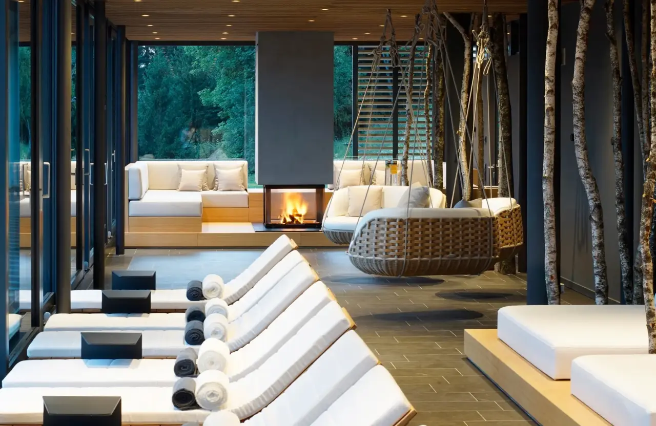 Hotel - DAS TEGERNSEE in Tegernsee – Entspannungsbereich mit Kamin und bequemen Liegen | Wellnesshotel Tegernsee