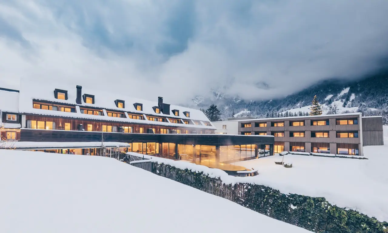 TRAUBE BRAZ Alpen.Spa.Golf.Hotel in Braz – Hotelanlage im Winter mit Schnee und Alpenkulisse | Wellnesshotel Vorarlberg