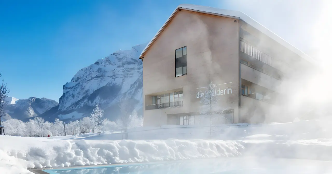 Hotel die Wälderin in Mellau – Winteransicht mit dampfendem Außenpool und Bergpanorama | Wellnesshotel Bregenzerwald