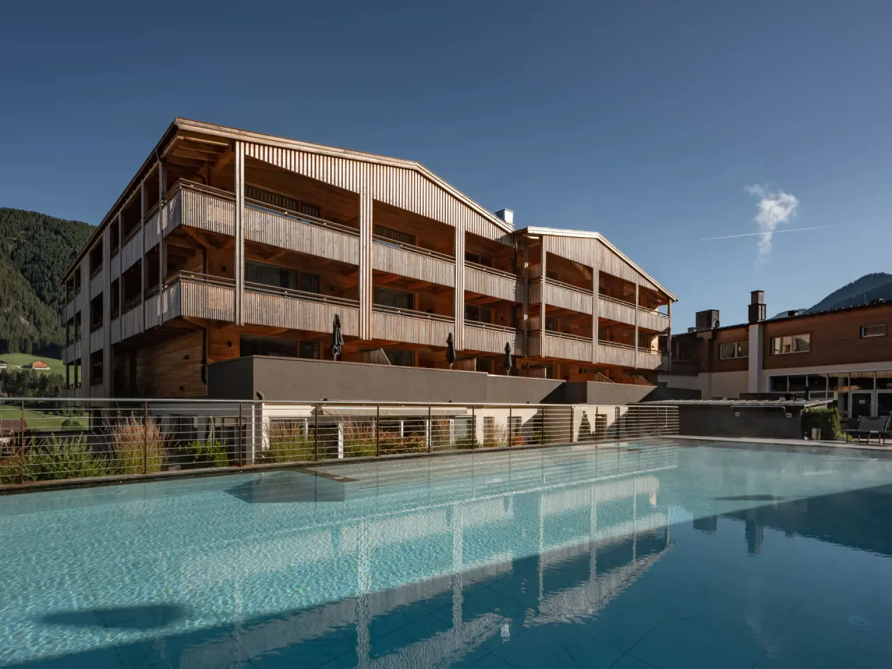 Alpine Nature Hotel Stoll in Toblach – Moderne Hotelfassade mit Außenpool | Wellnesshotel Südtirol