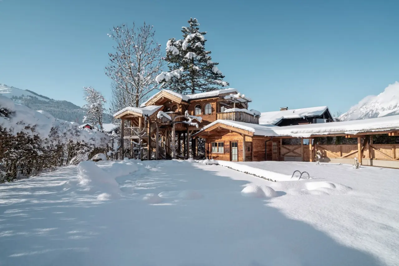 Hotel Hochfilzer in Ellmau – Holzgebäude im verschneiten Garten mit Winterlandschaft | Wellnesshotel Tirol