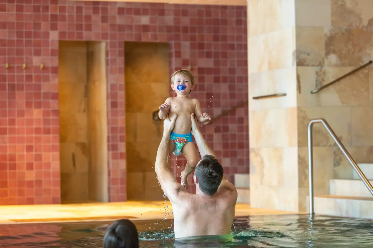 Hotel Sonnenburg in Lech am Arlberg – Vater spielt mit Kind im Innenpool | Wellnesshotel Arlberg