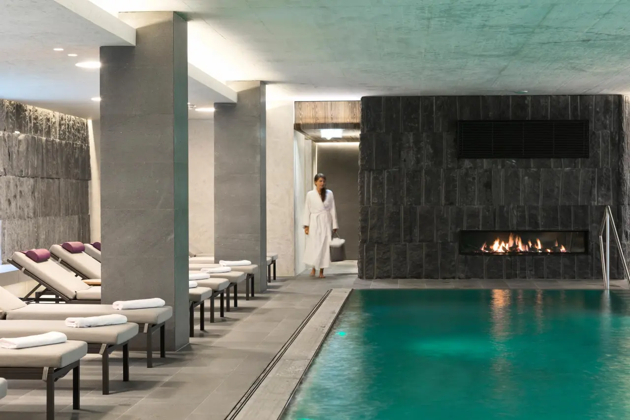 ElisabethHotel in Mayrhofen – Entspannender Innenpoolbereich mit Kamin und Liegen | Wellnesshotel Zillertal