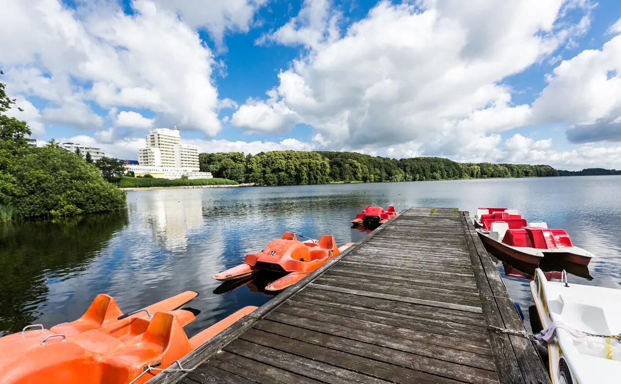 Vitalia Seehotel in Bad Segeberg – Seeufer mit Tretbooten und Hotelgebäude im Hintergrund | Wellnesshotel Holsteinische Schweiz