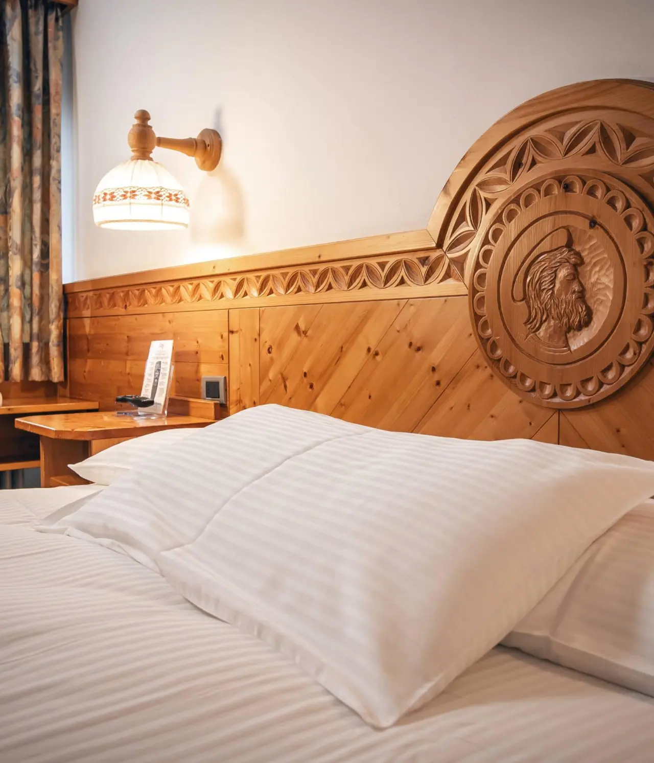Hotel Elgus Nature Retreat in Brentonico – Detailaufnahme Holzbett mit Schnitzerei | Wellnesshotel Trentino