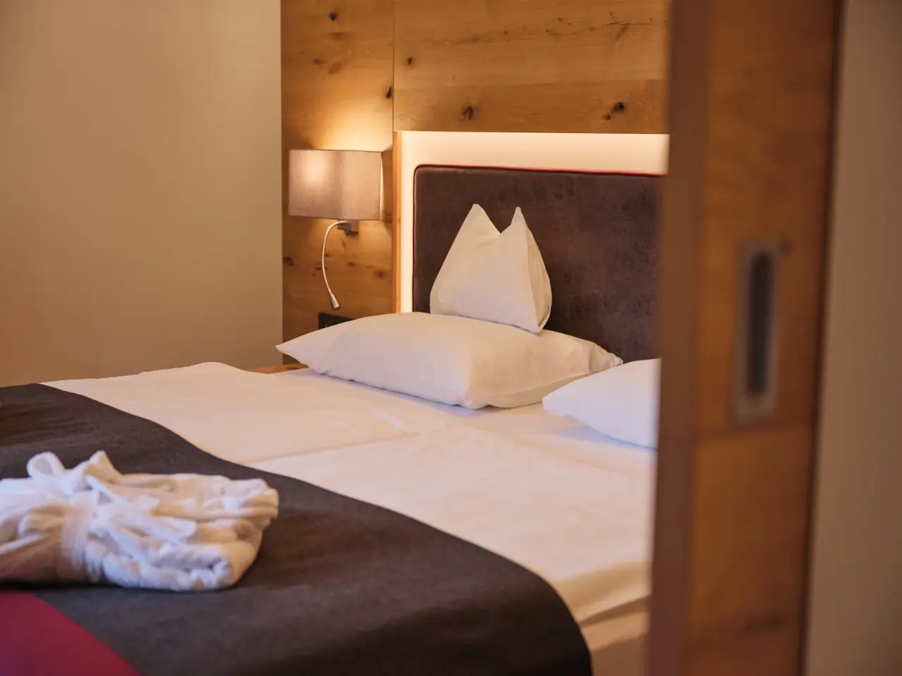 Sporthotel Wagrain in Wagrain – Detailansicht eines gemütlichen Bettes mit Bademantel | Wellnesshotel Salzburg