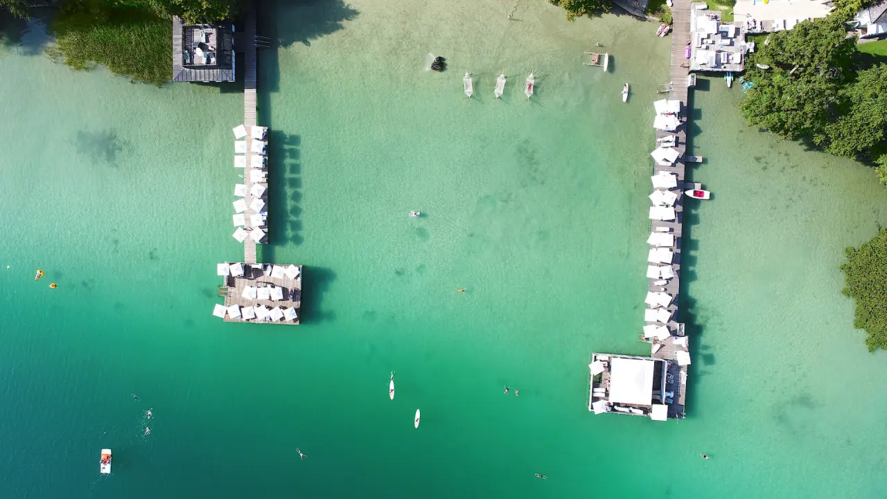 Wellnessresort Amerika-Holzer am See in St. Kanzian – Luftbild mit Badestegen und türkisem See | Wellnesshotel Kärnten