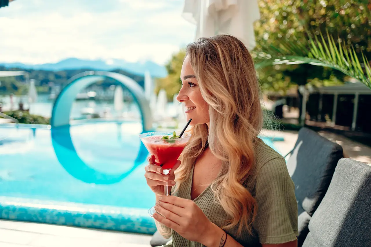Wellnessresort Amerika-Holzer am See in St. Kanzian – Frau mit Cocktail am Hotelpool | Wellnesshotel Kärnten