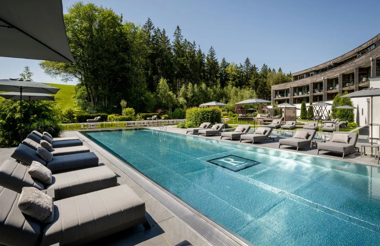 Wellness & Naturresort Reischlhof in Wegscheid – Großer Außenpool mit Liegen und Hotelgebäude | Wellnesshotel Bayerischer Wald