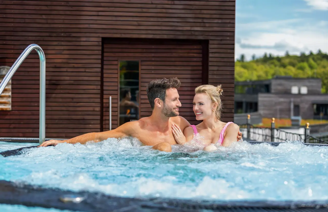 Wellness & Naturresort Reischlhof in Wegscheid – Glückliches Paar entspannt im warmen Whirlpool | Wellnesshotel Bayerischer Wald