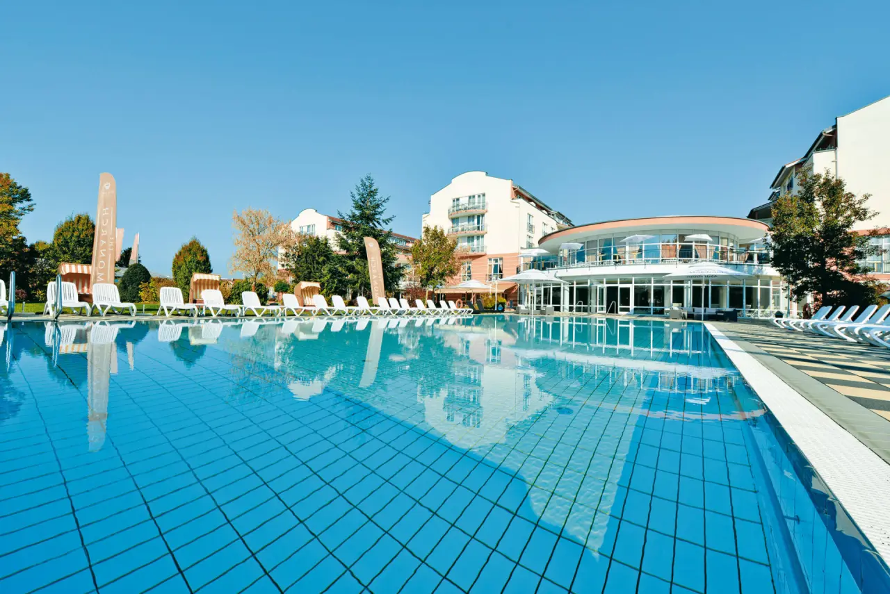 The Monarch Hotel in Bad Gögging – Großer Außenpool mit Liegebereich und Hotelgebäude | Wellnesshotel Niederbayern