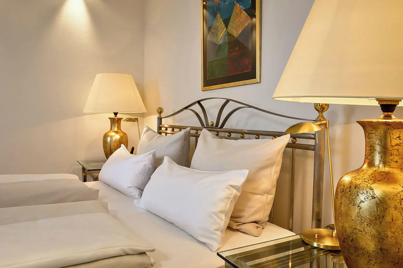 The Monarch Hotel in Bad Gögging – Detailansicht des Bettes mit Nachttischlampen im Hotelzimmer | Wellnesshotel Niederbayern