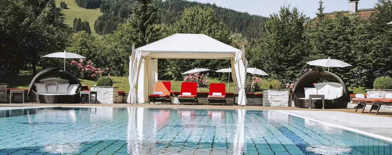 Hotel Gut Weissenhof Radstadt in Radstadt – Außenpool mit bequemen Liegen und Cabanas | Wellnesshotel Salzburger Land