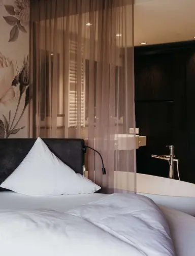 Hotel Rudolf in Bruneck – Modernes Schlafzimmer mit Badewanne und floraler Tapete | Wellnesshotel Südtirol