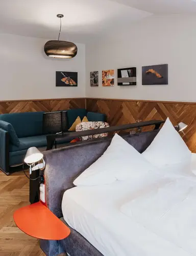 Hotel Rudolf in Bruneck – Geräumiges Hotelzimmer mit Bett und gemütlicher Sitzecke | Wellnesshotel Südtirol