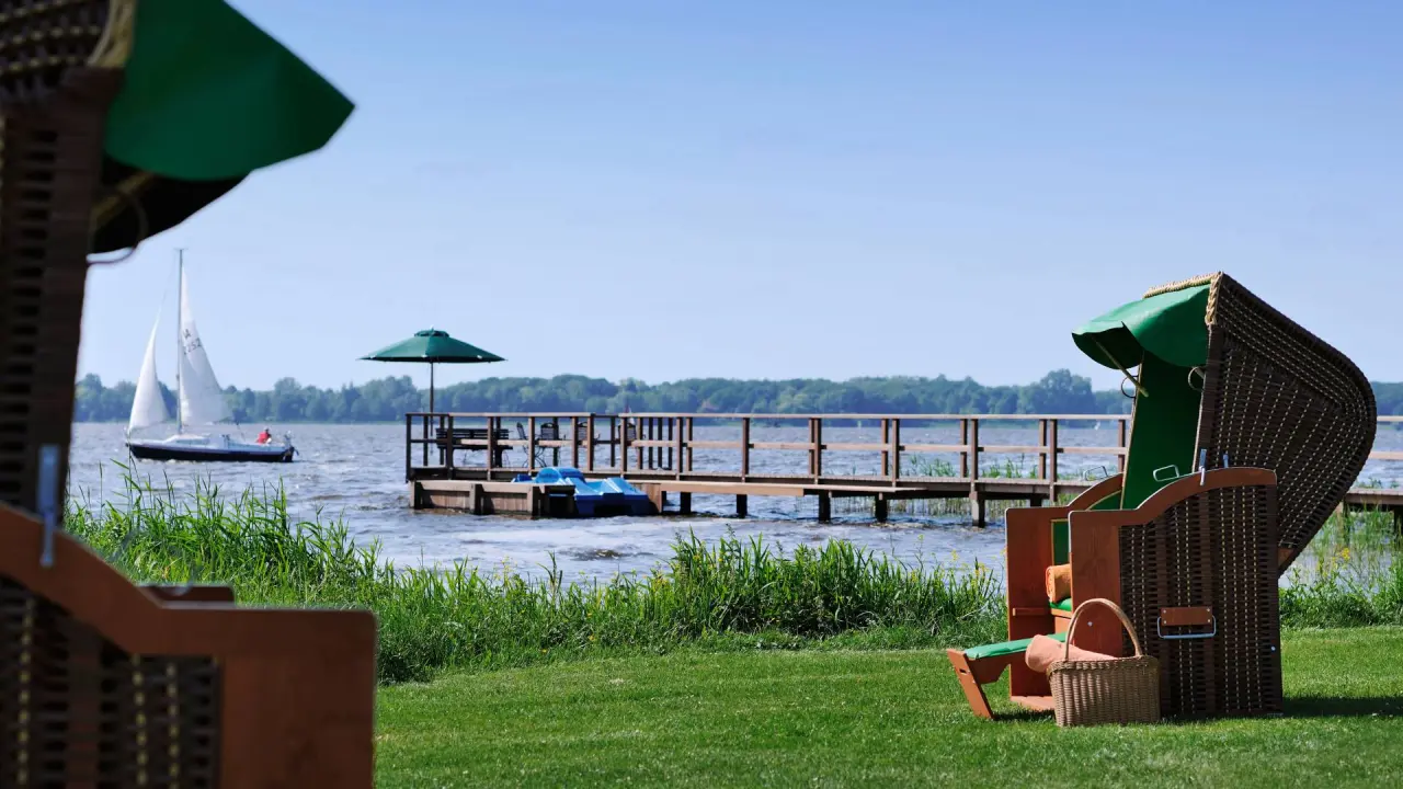 Romantik Hotel Jagdhaus Eiden in Bad Zwischenahn – Strandkörbe am Seeufer mit Segelboot | Wellnesshotel Ammerland