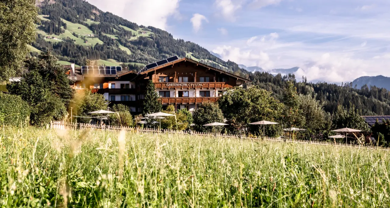 Gardenhotel Crystal in Fügen – Außenansicht des Hotels mit Bergpanorama und grüner Wiese | Wellnesshotel Zillertal