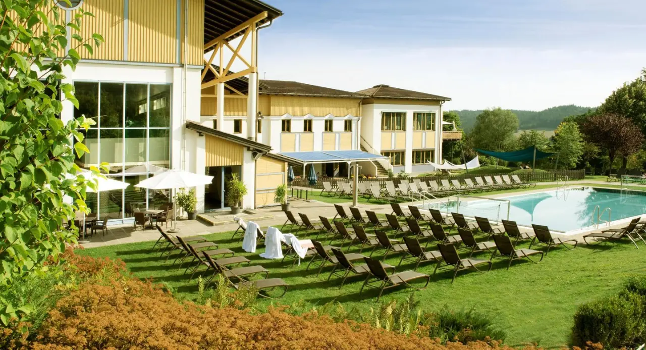 Aldiana Club Ampflwang in Ampflwang – Außenpool mit Liegewiese und Hotelgebäude im Sommer | Wellnesshotel
