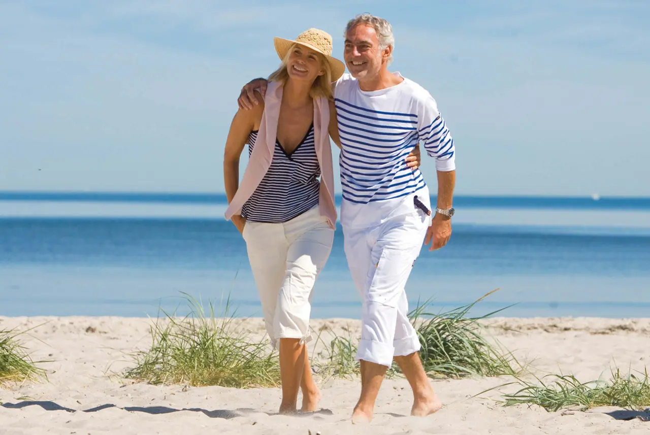 Yachthafenresidenz Hohe Düne in Rostock-Warnemünde – Glückliches Paar beim Strandspaziergang | Wellnesshotel Ostsee