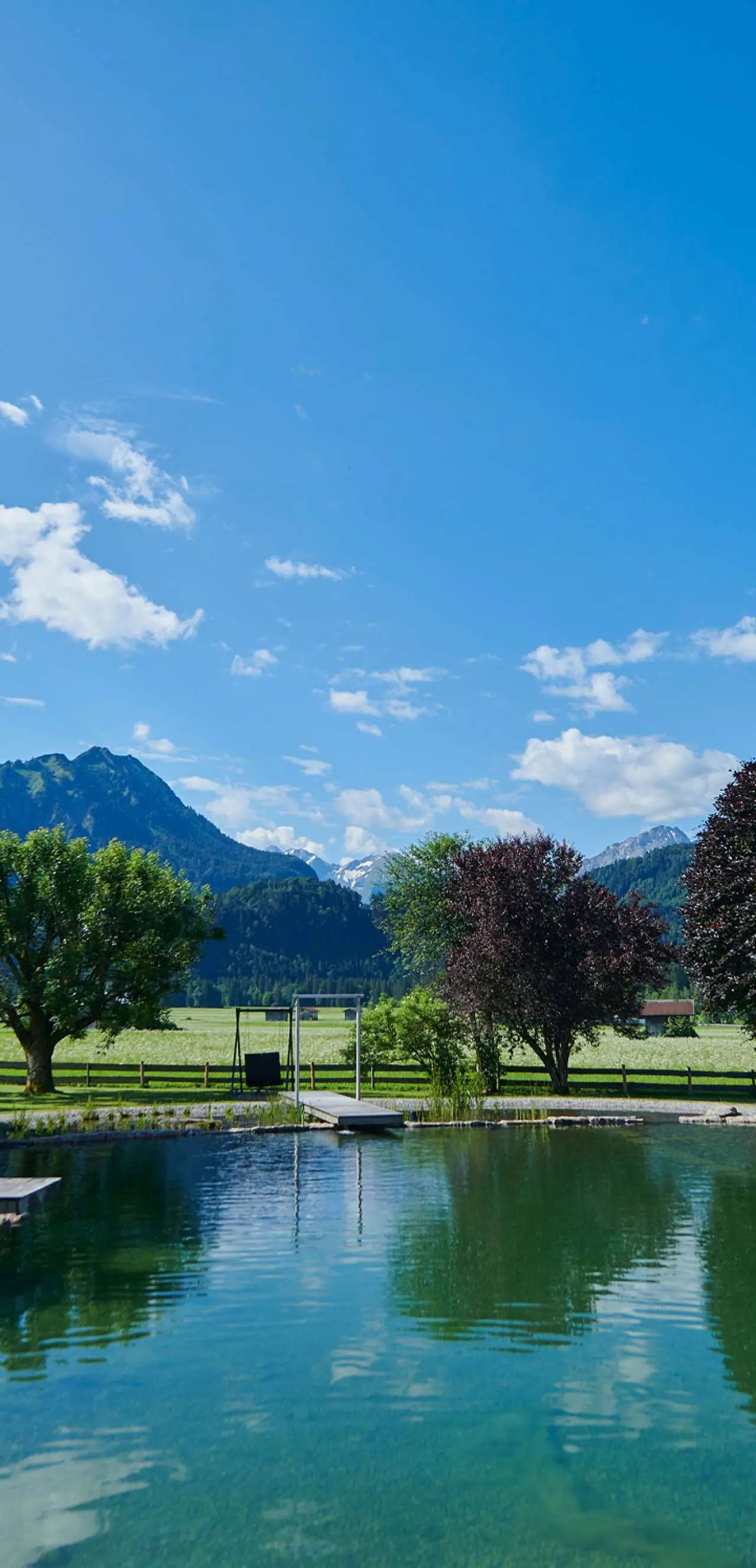 SCHÜLE'S Gesundheitsresort & Spa in Oberstdorf – Naturbadeteich mit Bergblick im Sommer | Wellnesshotel Allgäu