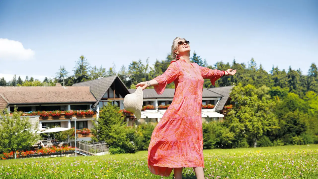 Hotel Grüner Wald****S in Freudenstadt – Glückliche Frau im Grünen vor dem Hotel | Wellnesshotel Schwarzwald