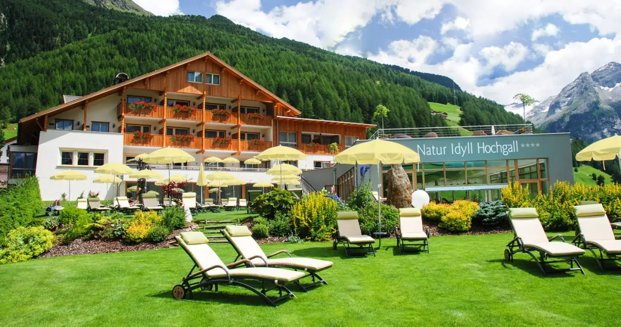 Das Auszeit-Hotel Natur Idyll Hochgall in Sand in Taufers – Außenansicht mit Garten und Bergen | Wellnesshotel Südtirol