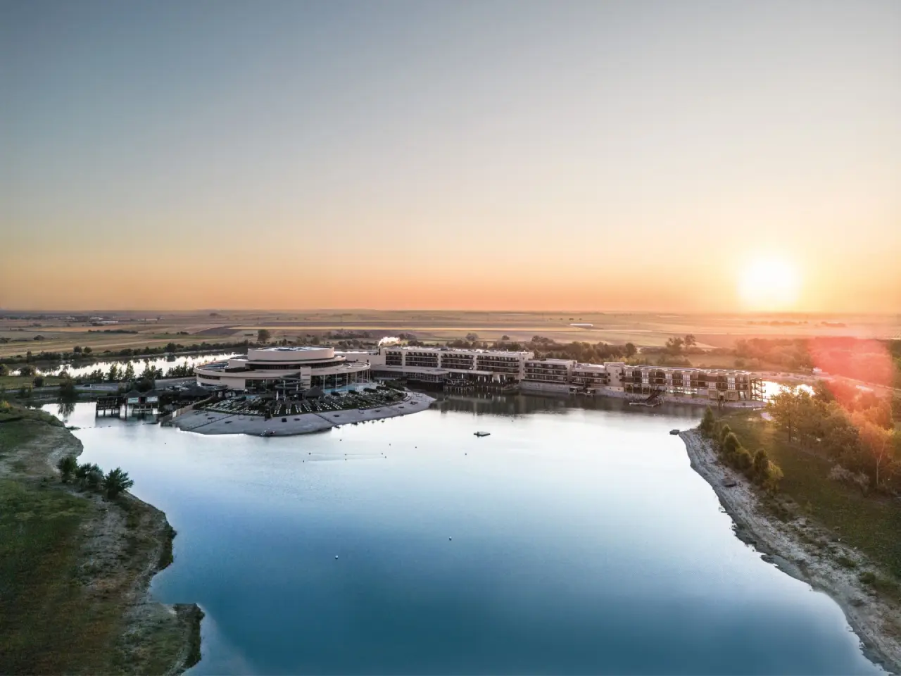 St. Martins Therme & Lodge in Frauenkirchen – Hotelanlage am See bei Sonnenaufgang | Wellnesshotel Burgenland