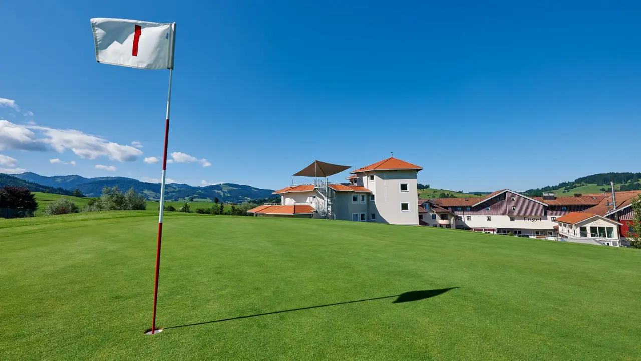 Dein Engel in Oberstaufen – Golfplatz mit Hotelgebäuden im Hintergrund an einem sonnigen Tag | Wellnesshotel Allgäu