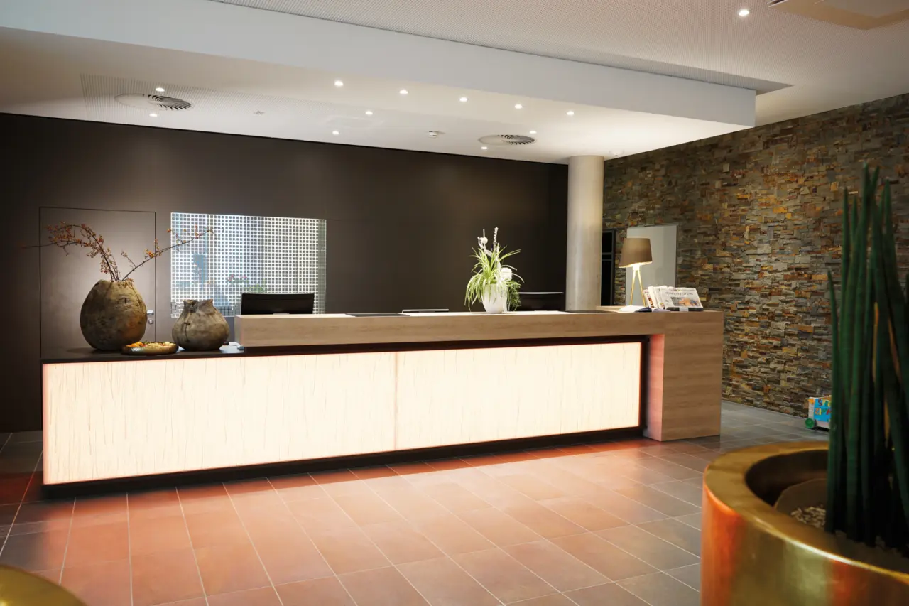 WONNEMAR Resort-Hotel Wismar in Wismar – Moderne Rezeption mit Holztheke und Steinwand | Wellnesshotel Mecklenburg-Vorpommern