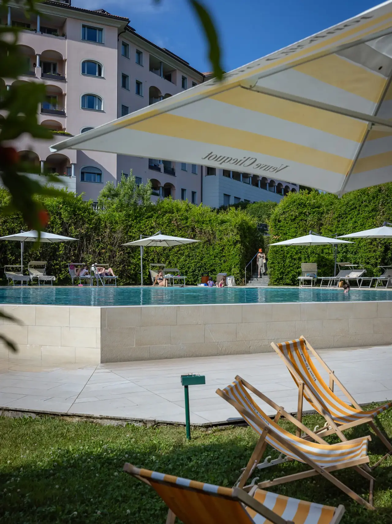 Resort Collina d'oro in Agra – Außenpoolbereich mit Liegestühlen und Sonnenschirmen | Wellnesshotel Tessin