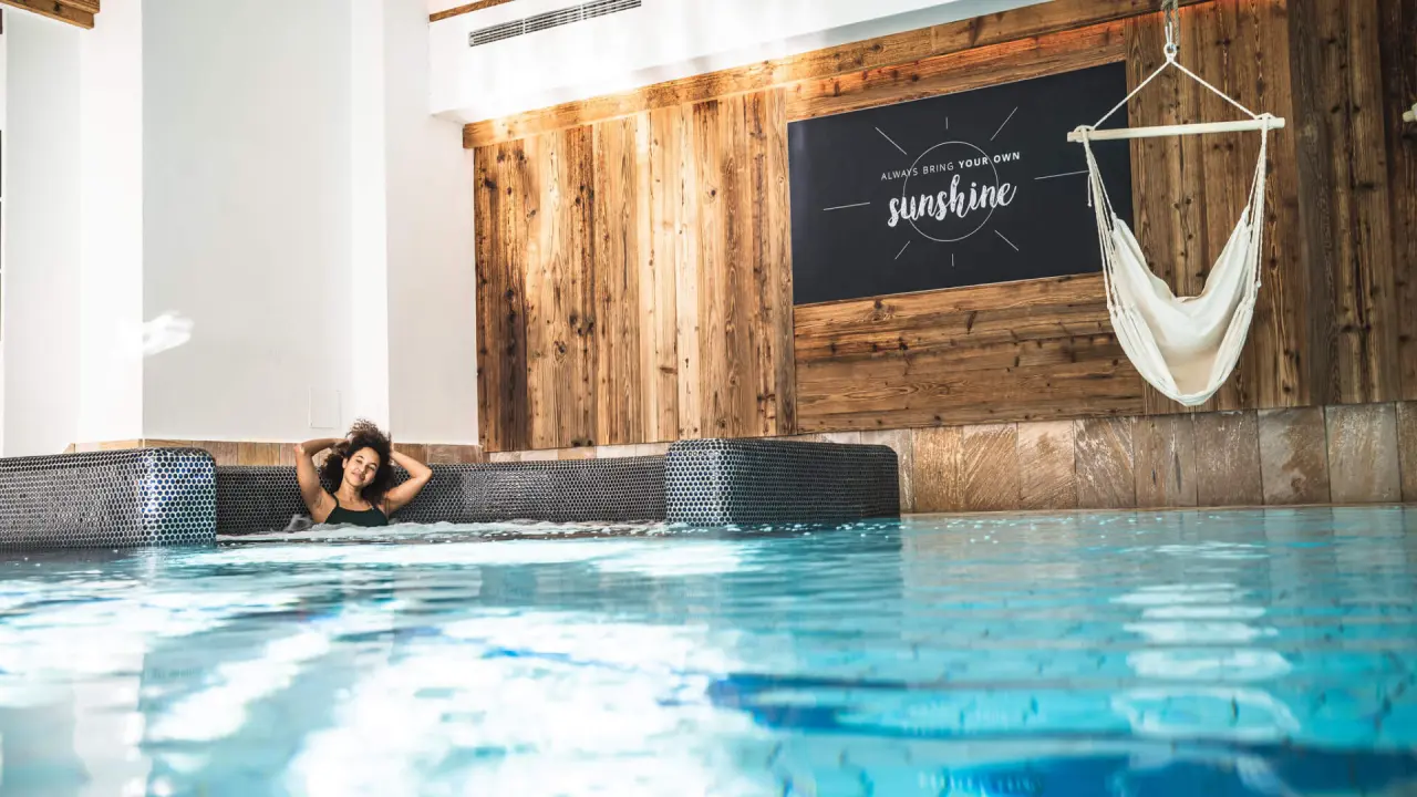 Das Falkenstein Kaprun in Kaprun – Entspannende Frau im Innenpool mit Holzdekor | Wellnesshotel Kaprun