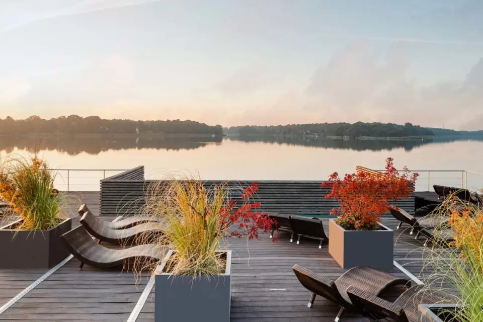 Resort Mark Brandenburg in Neuruppin – Sonnendeck am See mit Liegestühlen und Pflanzen | Wellnesshotel Brandenburg