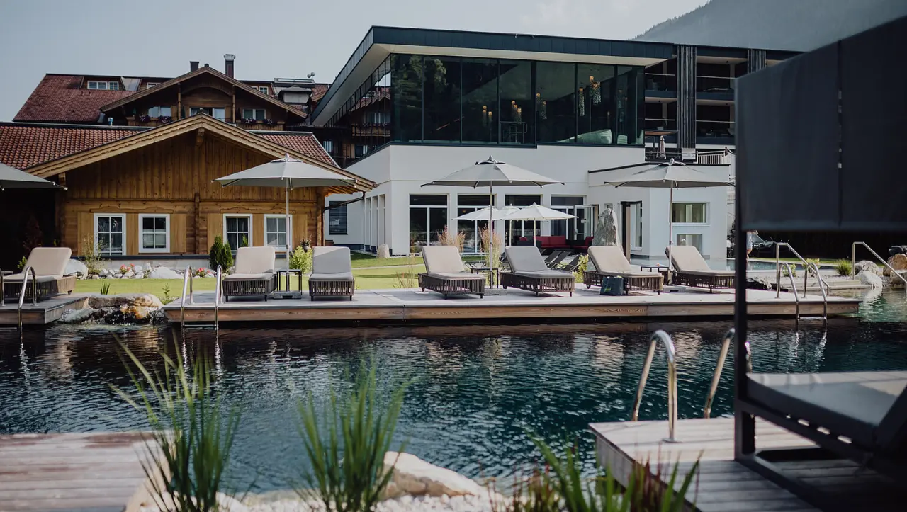 Alpin Life Resort Lürzerhof in Untertauern – Großzügiger Außenpool mit Liegen und Hotelgebäude | Wellnesshotel Salzburger Land