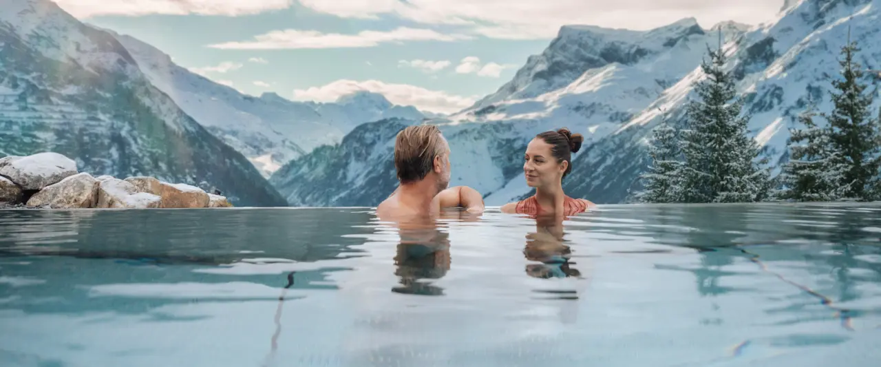 Hotel Goldener Berg in Lech am Arlberg – Paar im Infinity-Pool mit Alpenpanorama | Wellnesshotel Arlberg