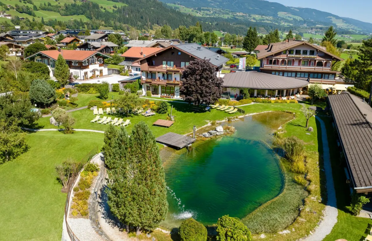 Wanderhotel Kirchner in Bramberg – Luftaufnahme des Hotels mit Naturbadeteich | Wellnesshotel Pinzgau