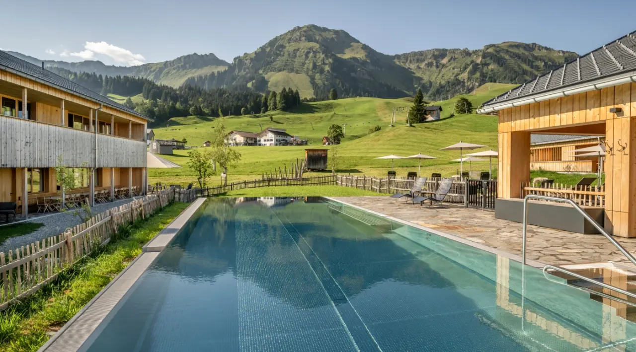 Fuchsegg Eco Lodge in Egg – Außenpool mit Liegen und Bergblick im Sommer | Wellnesshotel Bregenzerwald